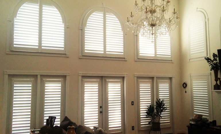 Television room in two-story Denver home with plantation shutters on high windows.