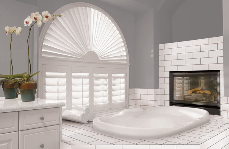 arch window with white polywood shutters in a large bathroom
