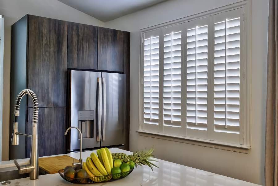 Homeowners use indoor window shutters in Denver when they want attractive and functional window treatments. Polywood shutters on a large kitchen window