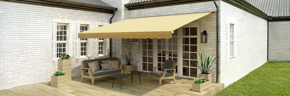 A beige retractable awing on a white brick house shading a wood deck