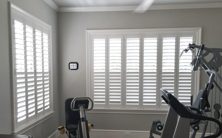 Weatherstripping window treatments are especially important in spaces with windows on multiple walls. Denver exercise room with shuttered windows.