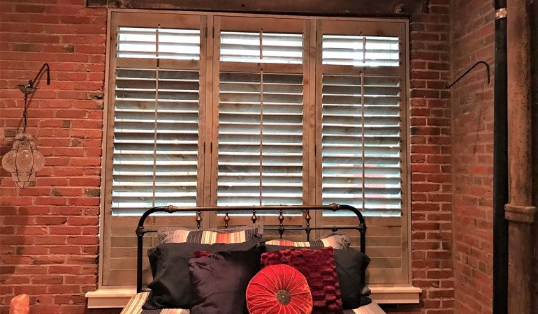 Reclaimed wood shutters add a natural feel to your minimalist spaces. Reclaimed wood shutters near a brick wall.