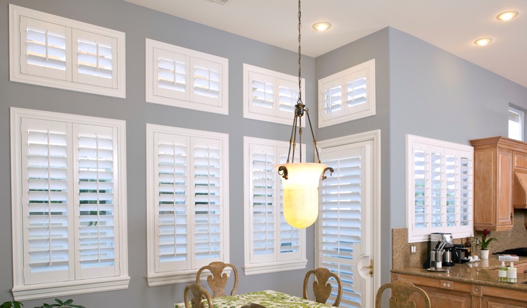 Shutters can solve both sun glare and energy efficiency problems. White plantation shutters in kitchen