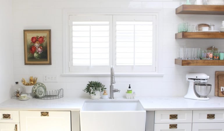 Polywood® plantation shutters look incredible in every kitchen. Plantation shutters over a farmhouse kitchen sink.