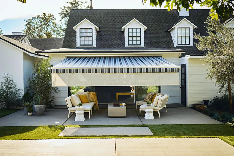  A black and white striped awning with a white front screen over a white stone patio