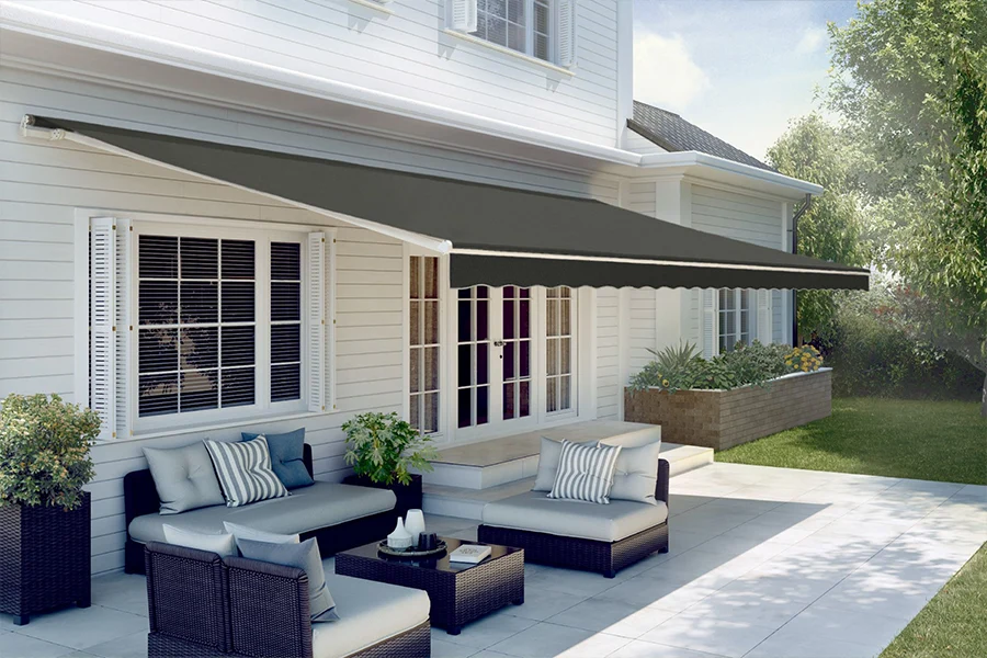 A dark gray retractable awning shading a white stone patio
