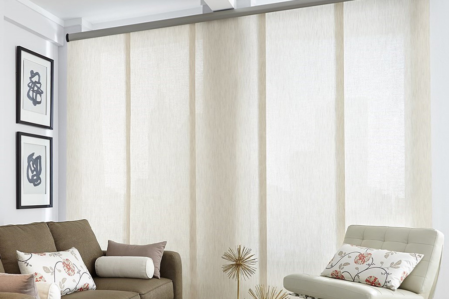 Find window treatments to complete any interior design among our extensive selection at Sunburst Shutters Denver.  Long off-white window shades on a tall window in a modern living room