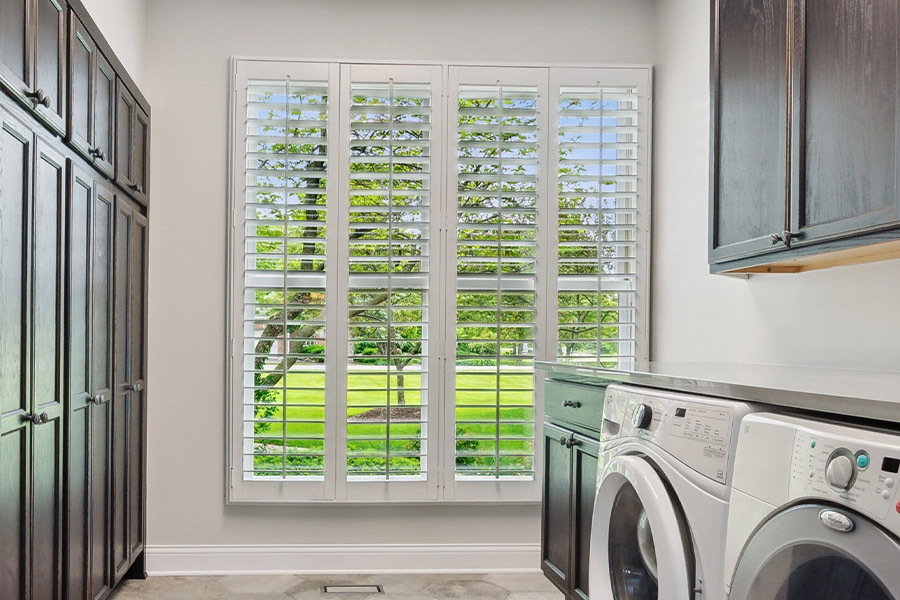 Find the perfect level of natural light for your Denver laundry room with interior shutters. White Polywood shutters letting light through a laundry room window