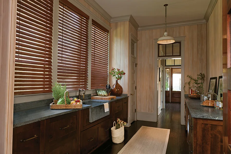 Sunburst's faux-wood blinds are perfect for high-moisture areas like bathrooms and kitchens. Chestnut faux-wood blinds on windows behind a kitchen sink